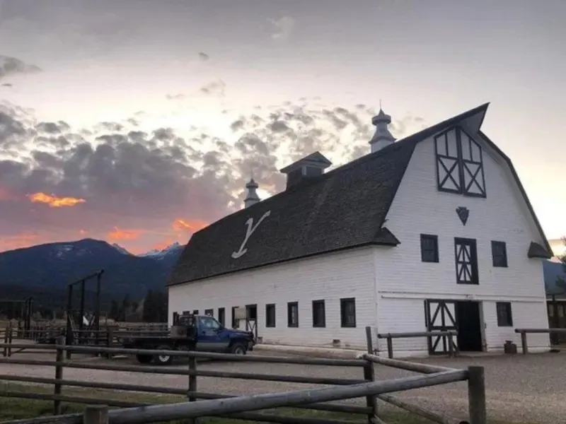 The white barn and corral fence under a pink sunset sky