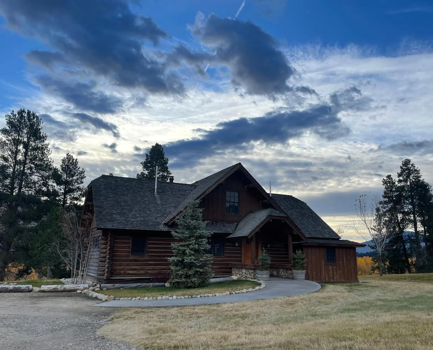 The Ben Cook Cabin, a log cabin with a covered entry, under a wide evening sky